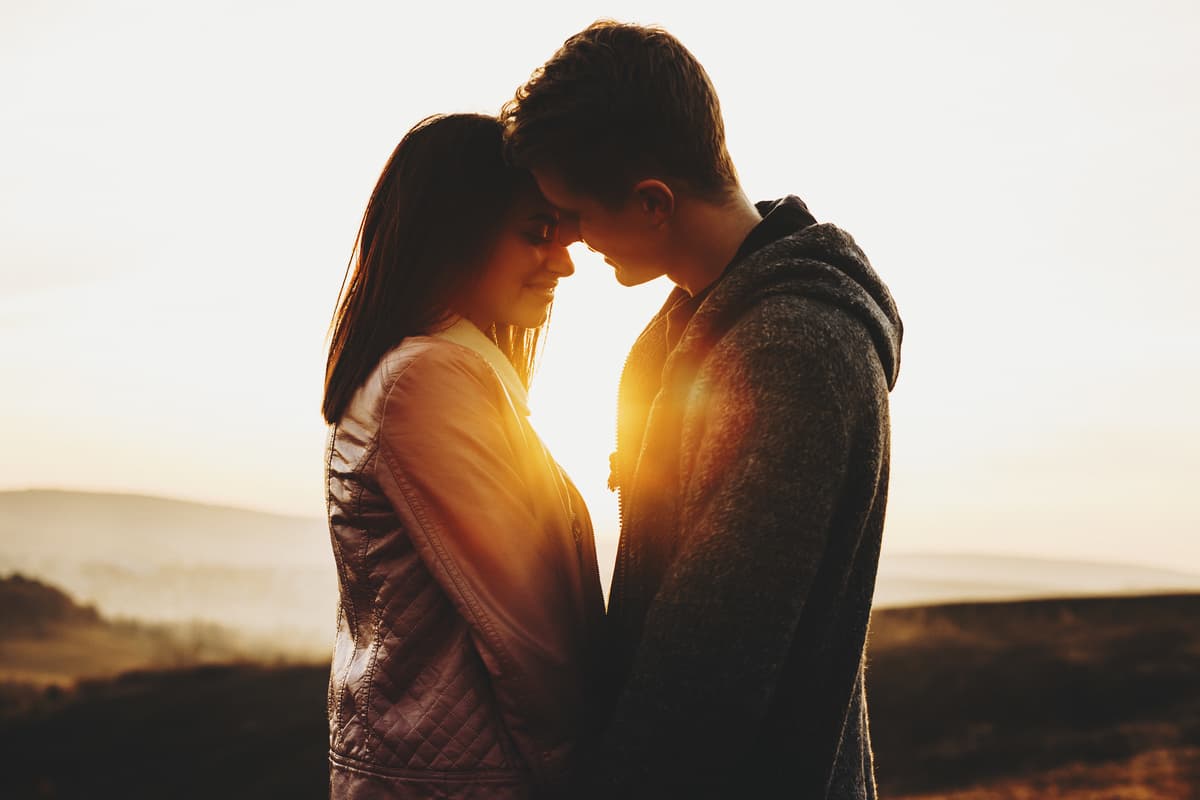 jeune couple s'embrassant au coucher du soleil