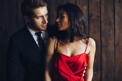 Femme sexy en robe de soirée rouge embrassant un homme