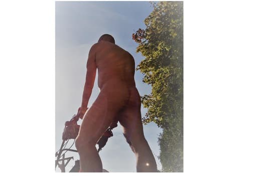 Homme tondant la pelouse nu